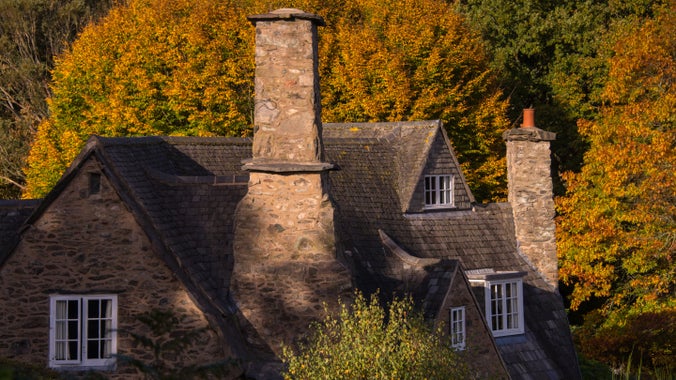 Cottage and woods in autumn light at Stoneywell Leciestershire